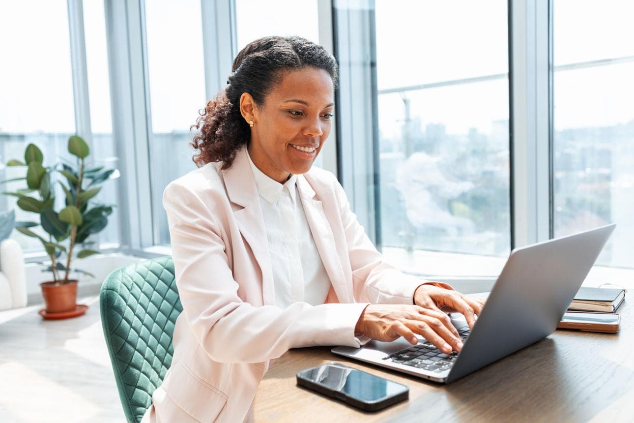 A professional typing on a laptop in a bright office